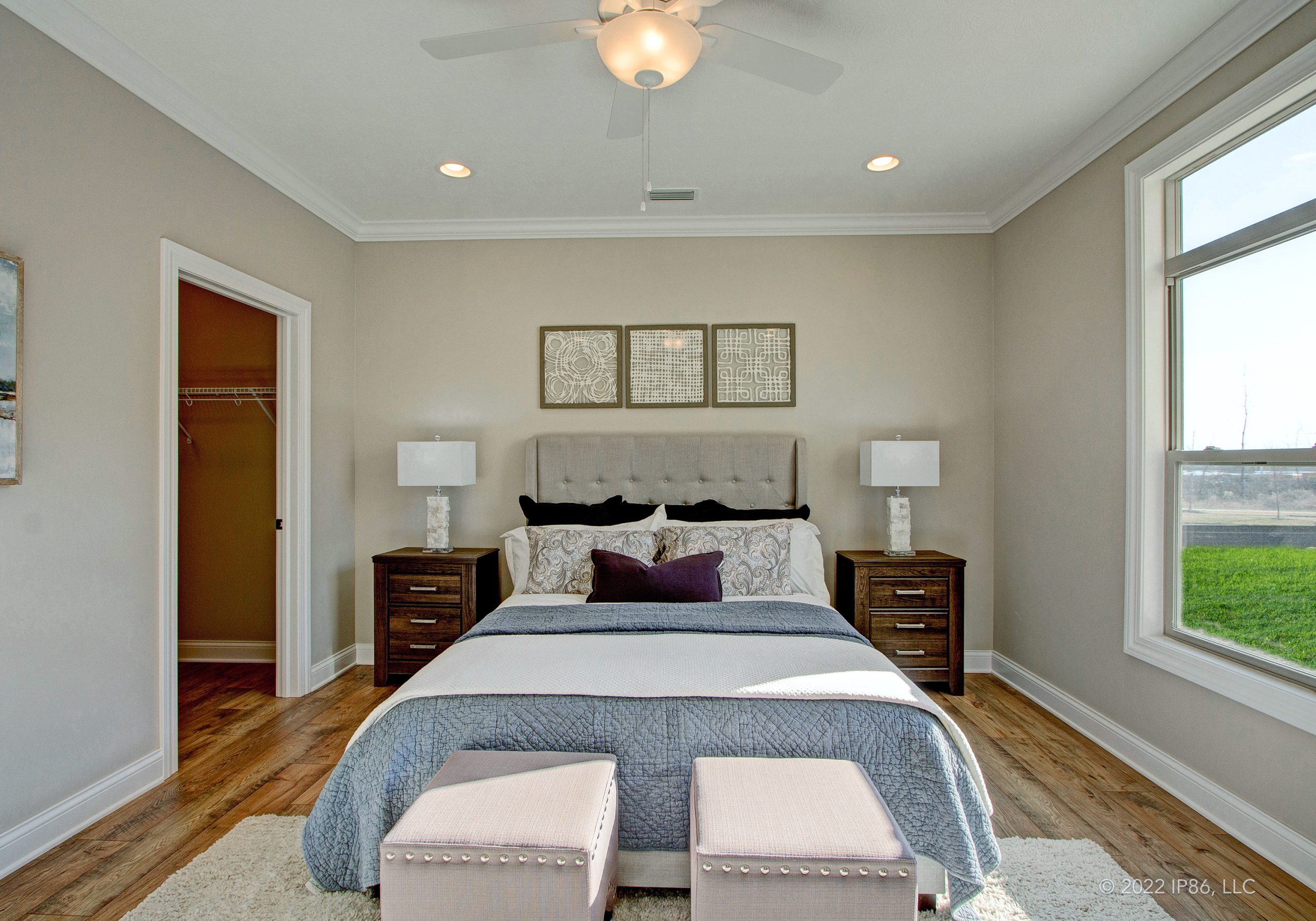 A stylish bedroom in The Capri model home featuring a bed, dresser, and a window allowing natural light.