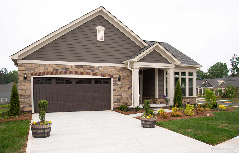 Palazzo model home exterior featuring stone, brick, and siding, with two-car garage and covered porch by New Leaf Homes