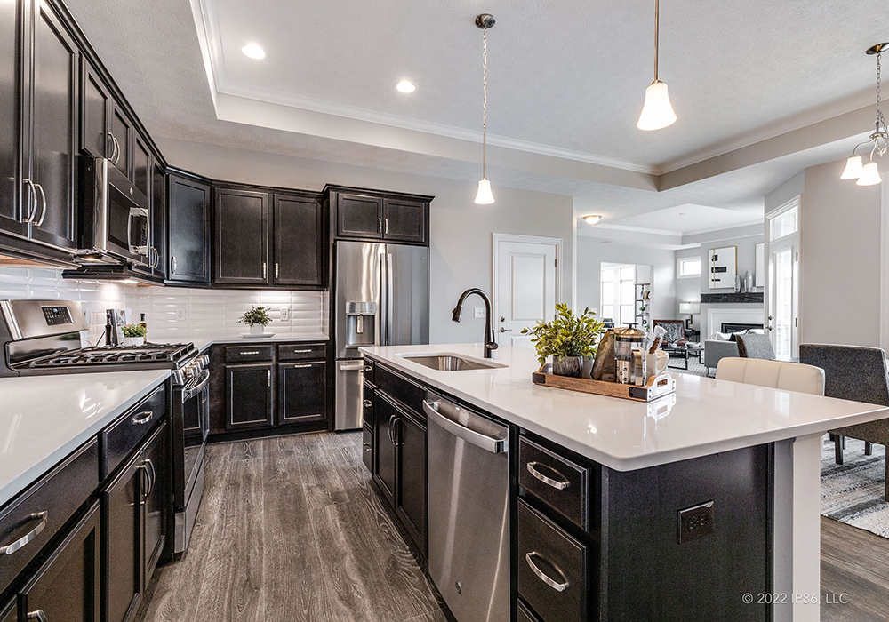 A modern kitchen featuring black cabinets and stainless steel appliances, designed as the Palazzo model by New Leaf Homes.