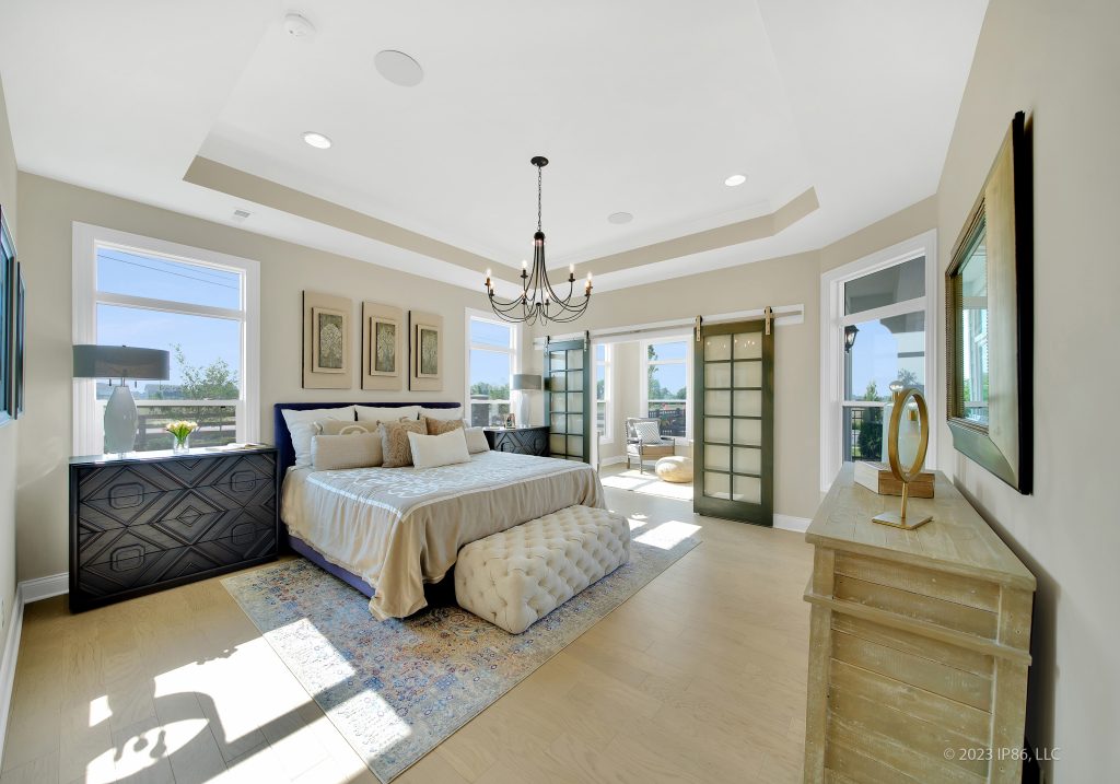 A spacious bedroom featuring a large bed and a window, showcasing the Palazzo model by New Leaf Homes.