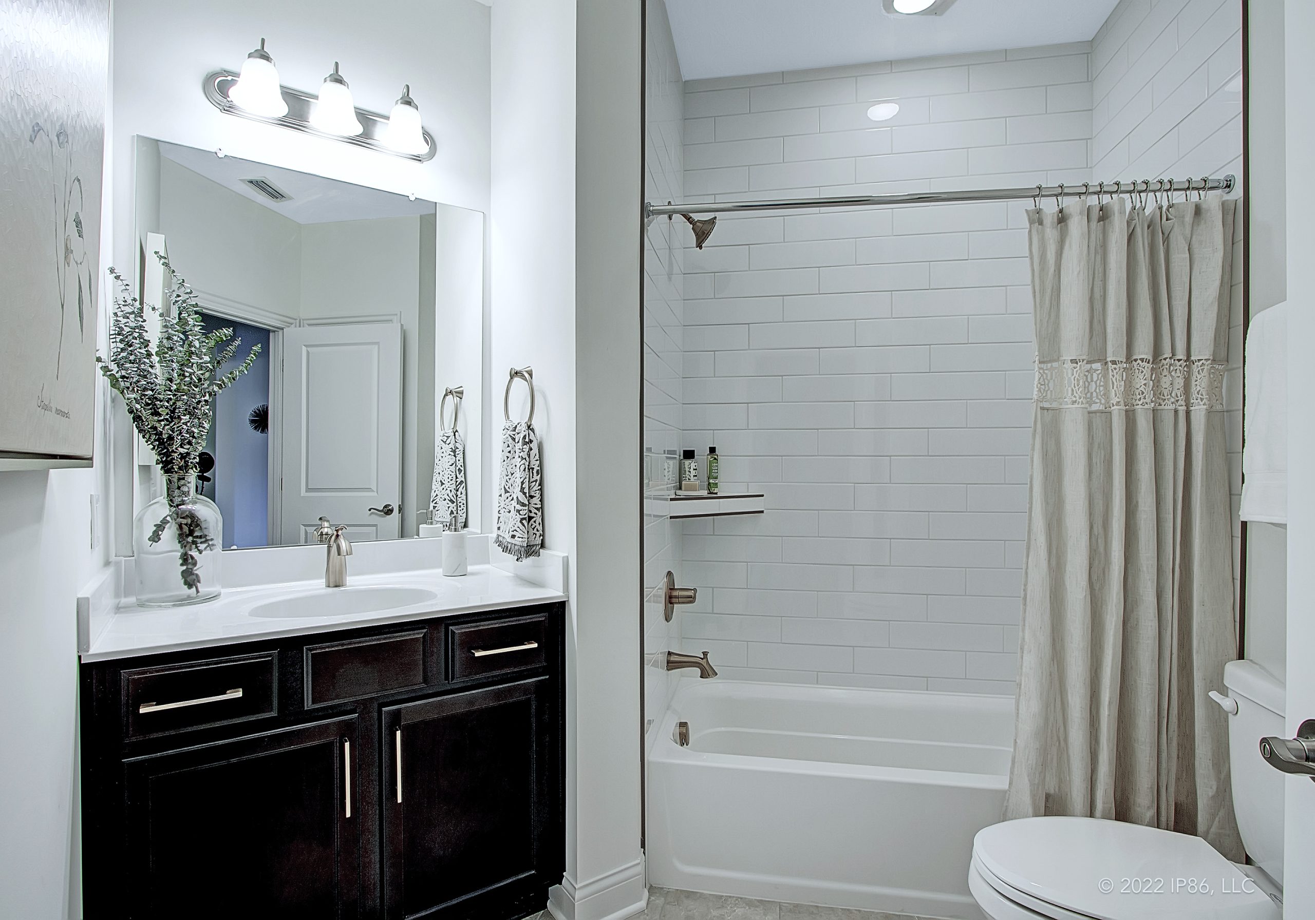 A modern bathroom featuring a shower, toilet, and sink, designed as the Promenade model by New Leaf Homes.