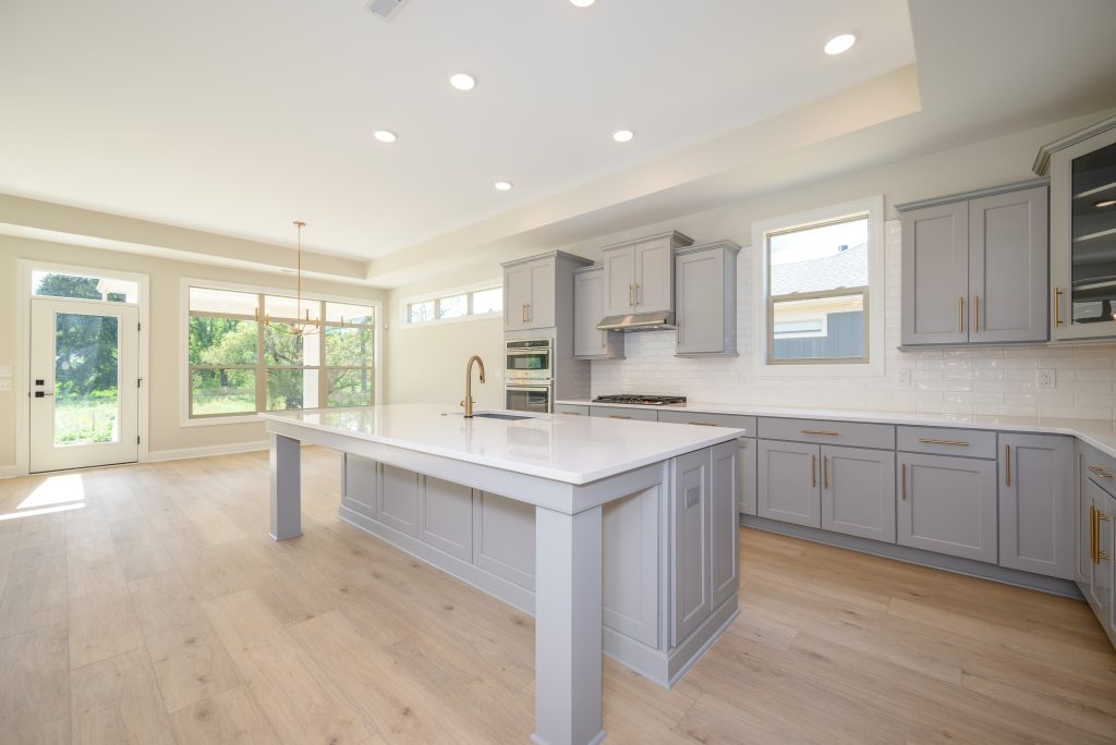 A Torino kitchen by New Leaf Homes in the move-in ready home located at 3348 Willow Lane, featuring a center island and elegant hardwood floors.
