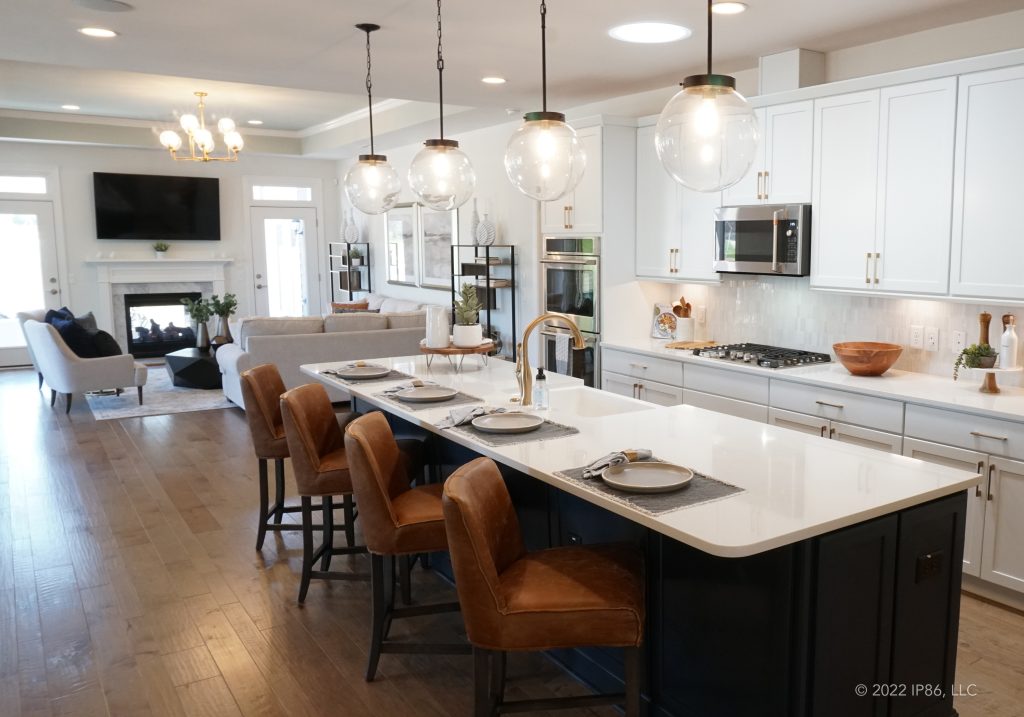 A modern kitchen featuring white cabinets and gray countertops, designed as the Verona model by New Leaf Homes.